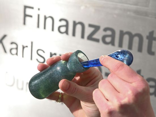 Vor dem Finanzamt Karlsruhe Stadt wird ein Flacon mit dem Parfüm „Aerarium“ gezeigt.