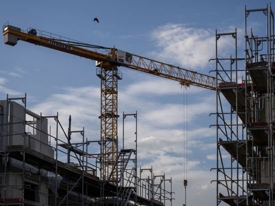 Ein Turmdrehkran ragt in den Himmel auf einer Baustelle zwischen neu errichteten Wohnhäusern: Die mittelständische Bauwirtschaft kämpft mit Problemen.