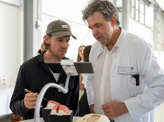 Am lebensechten Modell eines Gehirns aus Silikon erfährt  Ex-Formel-1-Fahrer Sebastian Vettel wie sich eine Hirn-Operation anfühlt. Angeleitet wird er vom Chef der Neurochirurgie am Städtischen Klinikum, Uwe Spetzer (rechts).
