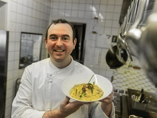 Marcello Gallotti in seiner Küche mit einem Teller Risotto.