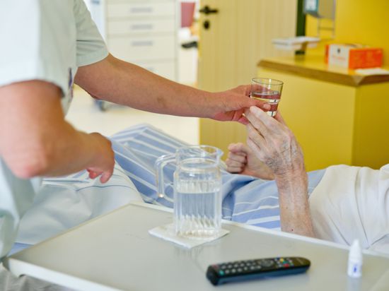 Eine Krankenpflegerin reicht einem Patienten ein Glas Wasser. (Zu dpa «Hitzewelle: Kliniken und Pflegeheime in Sachsen sind vorbereitet» ) +++ dpa-Bildfunk +++