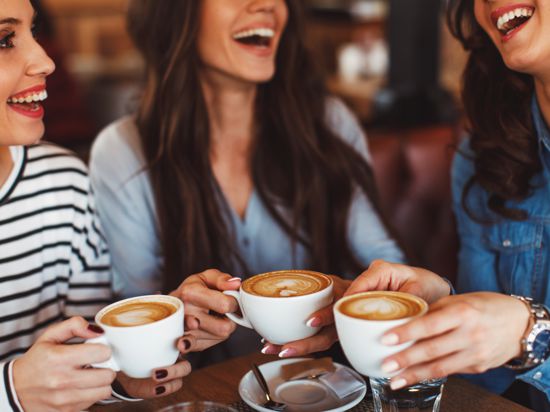 Three young women enjoy coffee at a coffee shop