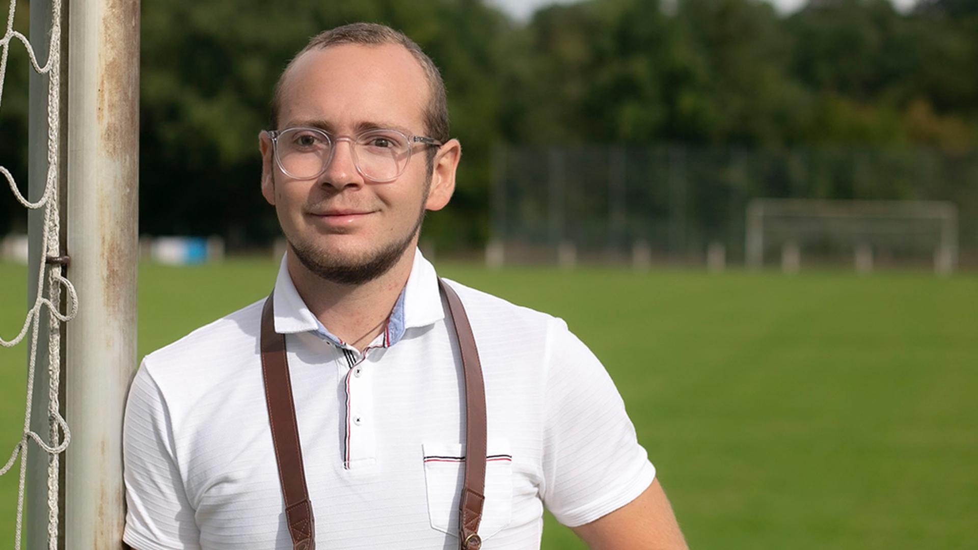 Alexander Schwarz, Mitglied im Fotoclub in Graben-Neudorf, steht mit seiner Kamera auf einem Fußballplatz.