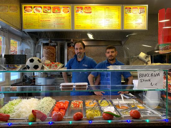 Wie wird es weitergehen: Erdal Sarialtun (rechts) und Tanko Senol vom Pizza & Kebabhaus in Linkenheim spüren die steigenden Preise deutlich. Wie lange das noch leistbar ist, ist für Sarialtun nicht absehbar. Die beiden Männer stehen hinter der Auslage eines Döner-Geschäftes.