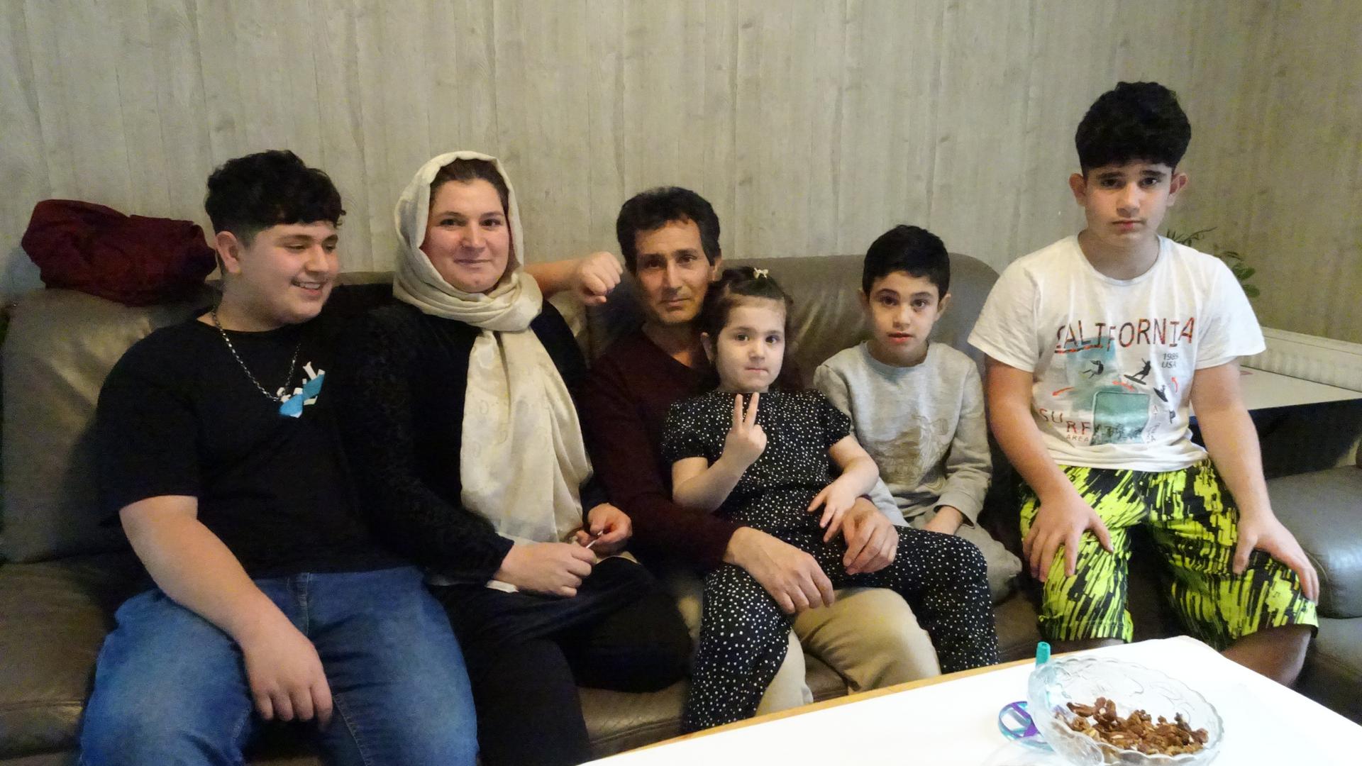 Familie mit vier Kindern sitzt im Wohnzimmer