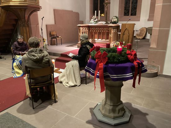 Drei Kirchenbesucher mit Decken vor dem Altar
