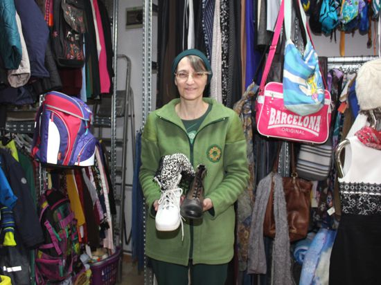 Frau mit Brille zeigt Schuhe in Second-Hand-Laden