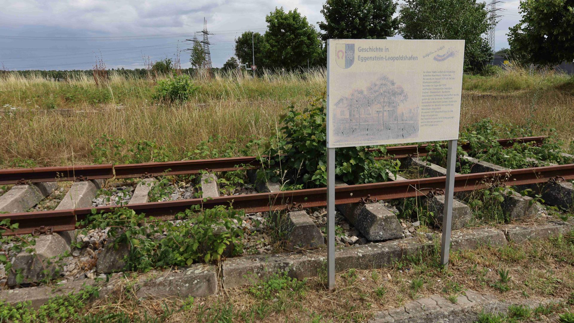 Eine Tafel informiert am ehemaligen Standort der Bahnhofs Leopoldshafen zur alten Hardtbahn. Das 2010 installierte Teil ist schon ziemlich verwittert.
