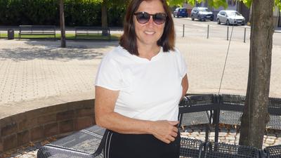 Dunkelhaarige Frau mit T-Shirt und Sonnenbrille auf öffentlichem Platz