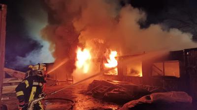Feuerwehrleute bekämpfen einen Brand in Wohncontainern beim Spargelhof Leicht in Eggenstein-Leopoldshafen. 