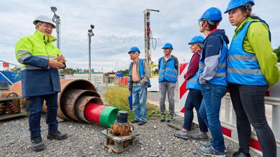 Roman Link und die Teilnehmer der Sommertour stehen auf der Baustelle des Geothemie-Kraftwerks.