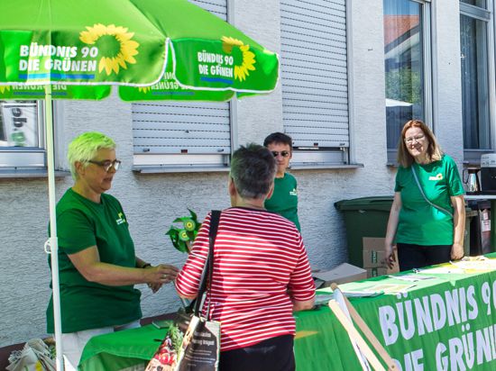 Stand der Grünen mit zwei Frauen und einem Mann vor einer Hausfront