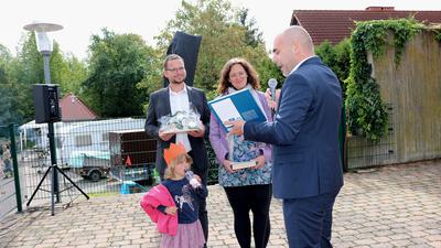 Bürgermeister Christian Eheim gratuliert Katja und Micha Willunat zur Übernahme der Pfarrstelle mit Henhöferhaus und überreicht ein Buch über Graben-Neudorf