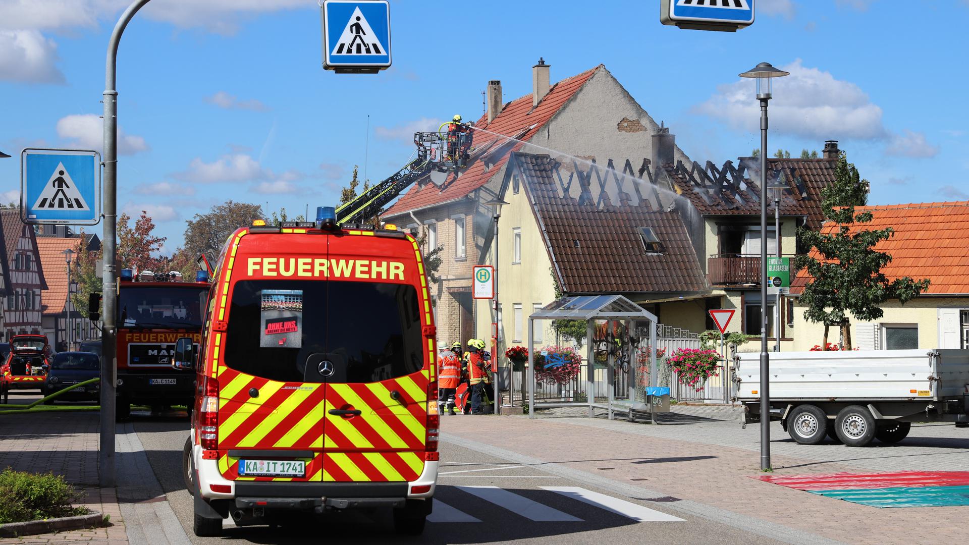 Ein Feuerwehrauto vor einem ausgebrannten Dachstuhl.