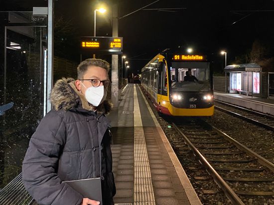 Mann mit Maske nachts am Bahnsteig, im Hintergrund eine Stadtbahn