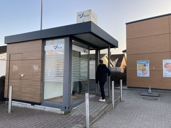 Ein Mann öffnet die Tür zum Geldautomaten der BBBank in Linkenheim-Hochstetten.
