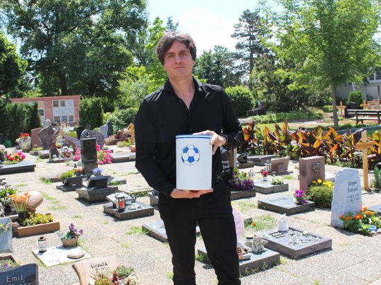 Bestatter Daniel Schütz auf dem Friedhof von Hochstetten, hier mit einer Urne für Fußball-Fans. Den Vorlieben der Verstorbenen wird heutzutage deutlich mehr Rechnung getragen.       