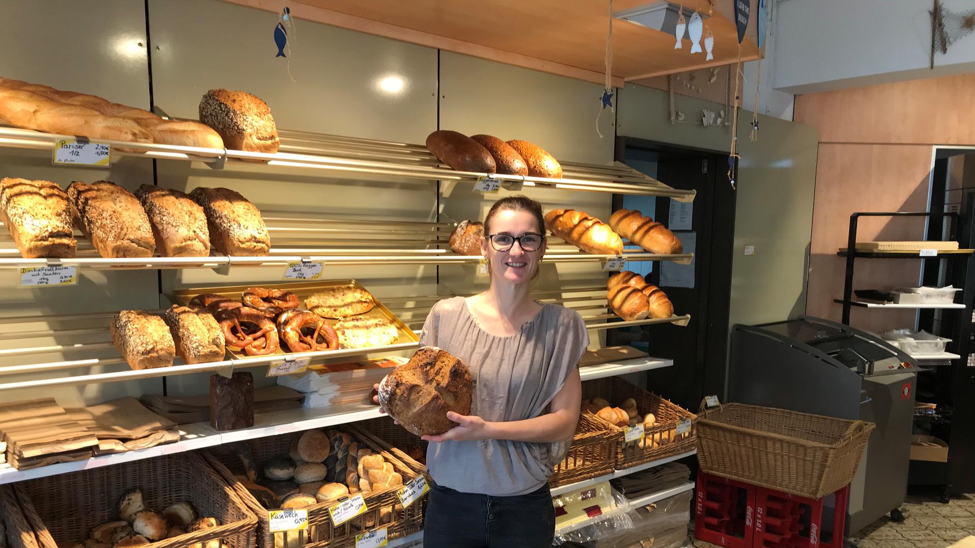 Nina Kienetz steht in ihrer Bäckerei und hält einen Laib Brot in der Hand. 