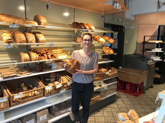 Nina Kienetz steht in ihrer Bäckerei und hält einen Laib Brot in der Hand. 