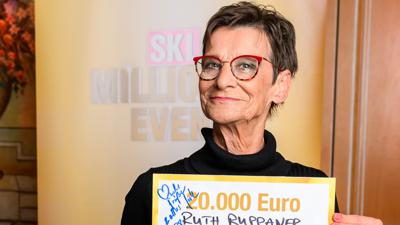 Eine Frau in schwarzem Pullover und mit roter Brille hält einen SKL-Scheck im Wert von 20.000 Euro hoch. 