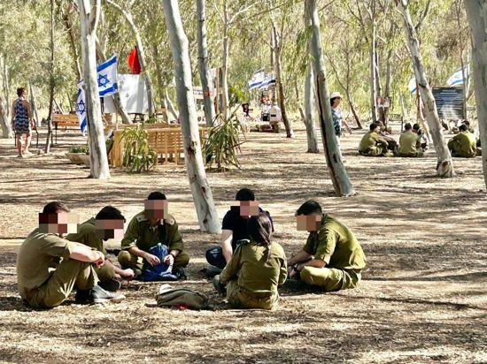 Menschen sitzen im Kreis auf dem Nova-Festival-Gelände in der Negevwüste im Süden Israels.