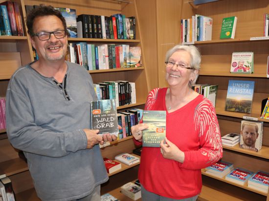 Andreas und Ingrid Mächtlinger stehen vor einem Bücherregal in der Bücheroase und halten jeweils ein Buch hoch. 