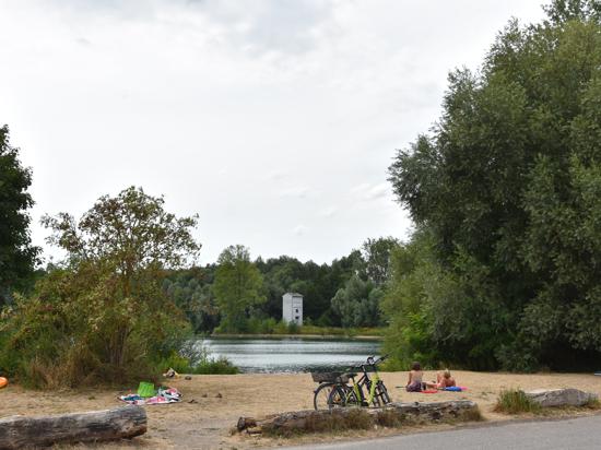 Zwei Menschen sitzen am Ufer eines Baggersees