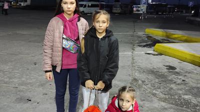 Drei Mädchen warten auf den Bus nach Deutschland. 