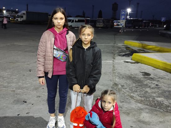 Drei Mädchen warten auf den Bus nach Deutschland. 