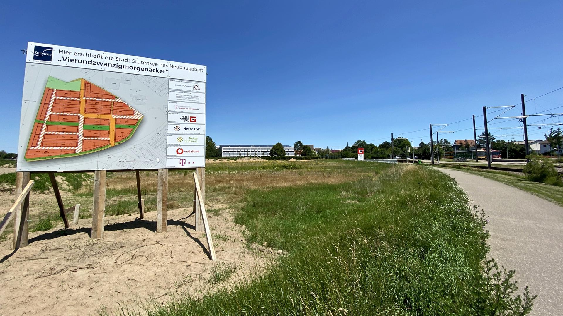 Großes Schild mit Plan, Grundstück, Schulgebäude im Hintergrund, Straßenbahnlinie