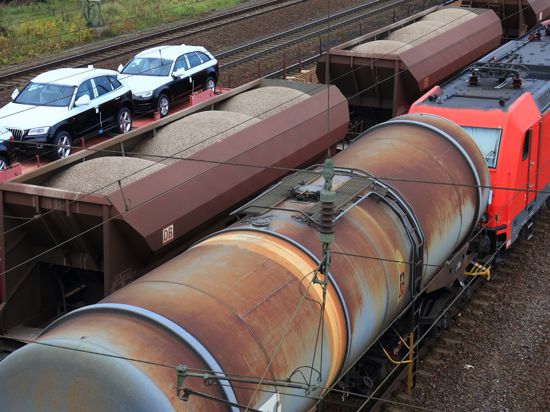 Eine Lokomotive zieht  einen Güterzug mit Kesselwagen in Magdeburg (Sachsen-Anhalt) an einem Zug mit Autos und einem mit Schüttgut vorbei.