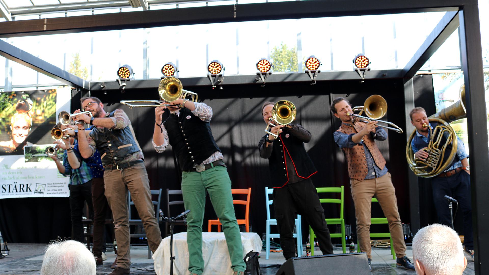 Drei Trompeter, drei Posaunisten und ein Tuba-Spieler stehen auf einer Bühne. 
