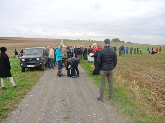 Eine Gruppe von Menschen versammelt sich auf einem Feld. 
