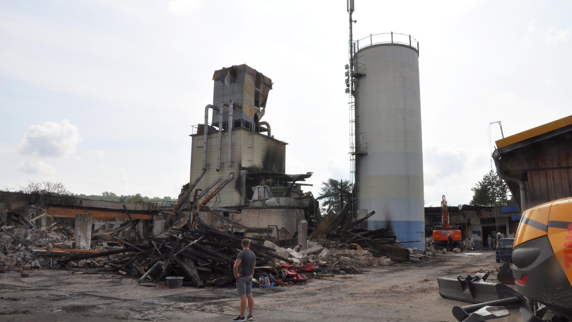 Zwei Industrieanlagen auf einer Gewerbebrache, umgeben von verbrannten Gebäuderesten nach Großbrand.