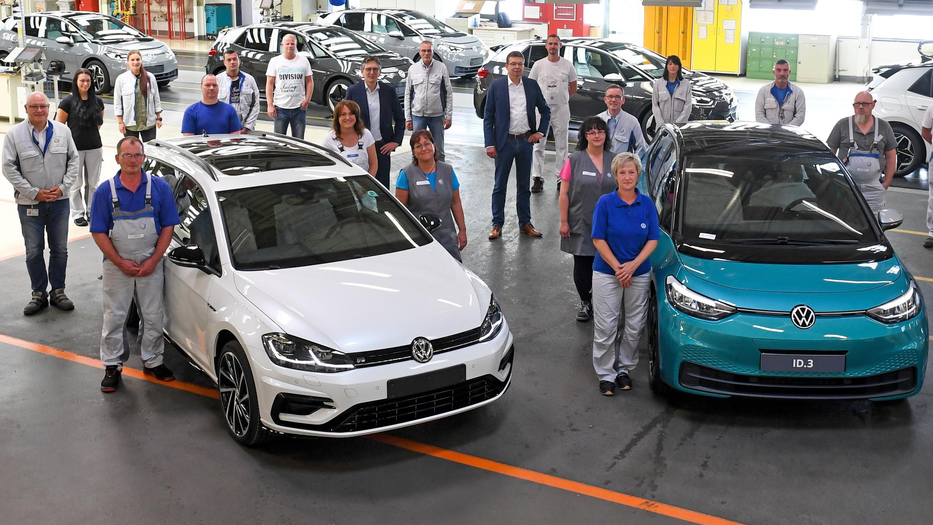  Mitarbeiter des Werkes von Volkswagen Sachsen stehen im Finish der Linie um einen VW Golf Variant und neben dem neuen ID.3. 
