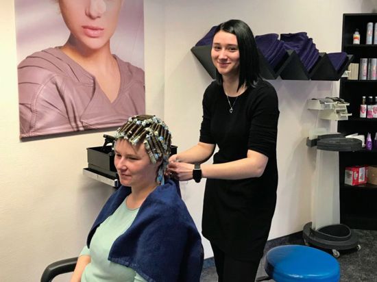 Eine junge Frau macht einer Frau in einem Friseursalon eine Dauerwelle