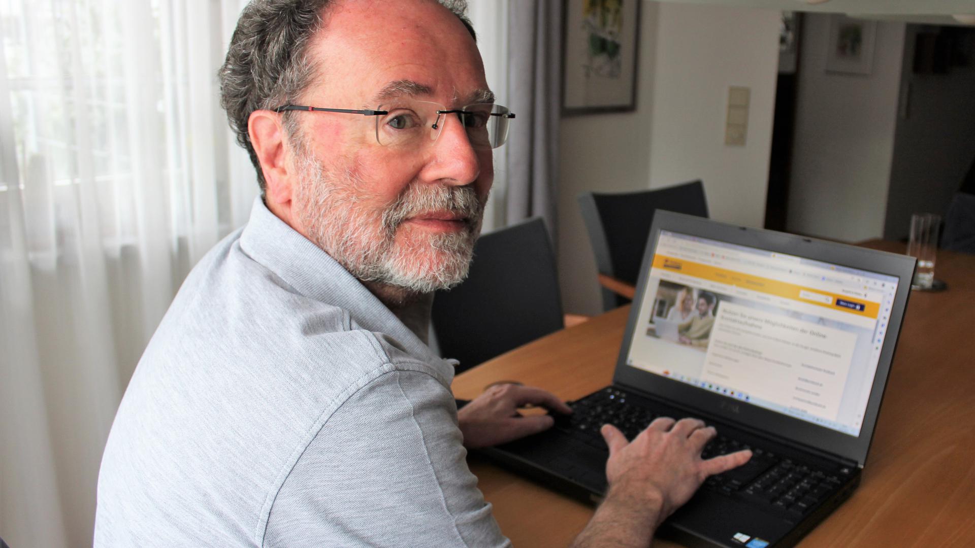 Fritz Liebersbach sitzt vor seinem Laptop, auf dem Bildschirm ist die Webseite der Postbank zu sehen. 
