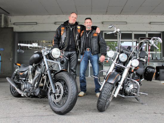 Andreas Dörr (links) und Oliver Bodrogi stehen in Newborn-Bikers-Jacke und Kutte neben ihrem Motorrädern. 
