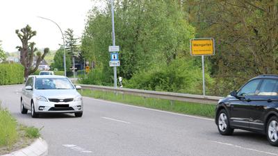 Autos fahren auf der Ortsausfahrt Weingarten (Baden). Das gelbe Ortsschild zeigt „Weingarten, Kreis Germersheim“