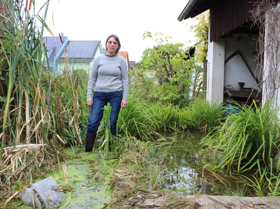 Edeltraud Malsch steht mit Gummistiefeln knöcheltief im Wasser in ihrem Garten. 