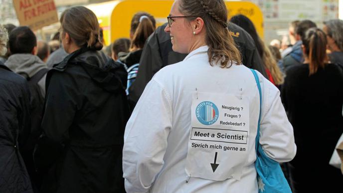 "Triff eine Wissenschaftlerin" steht auf dem Schild auf dem Rücken dieser Demonstrantin.