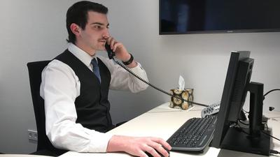Ein Mann in Anzug am Telefon und Computer gleichzeitig
