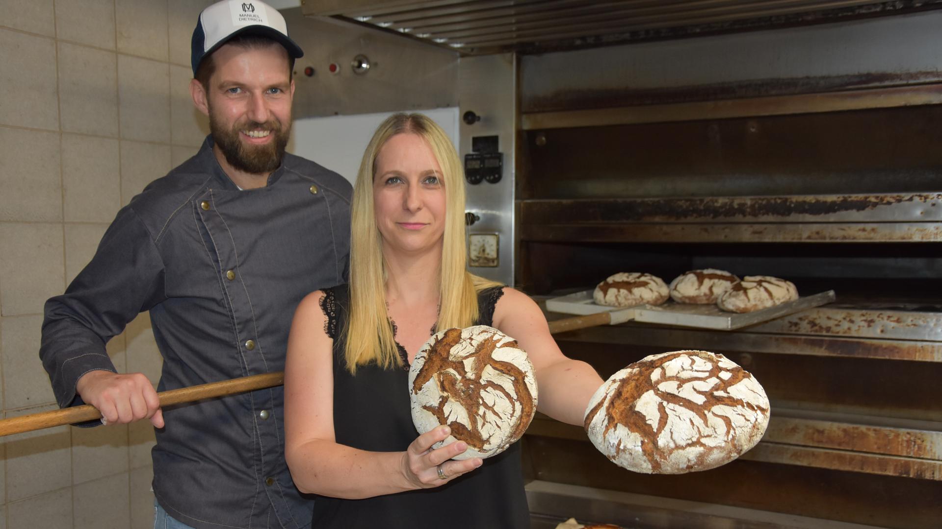 Ehepaar steht vor großem Ofen mit Brot und Brezeln