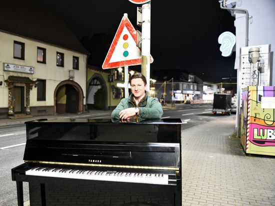 Mann steht hinter Klavier bei Dunkelheit an Bundesstraße