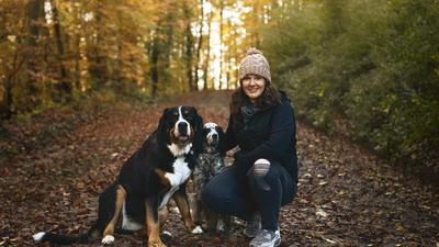 Frau mit zwei Hunden auf einem Waldweg