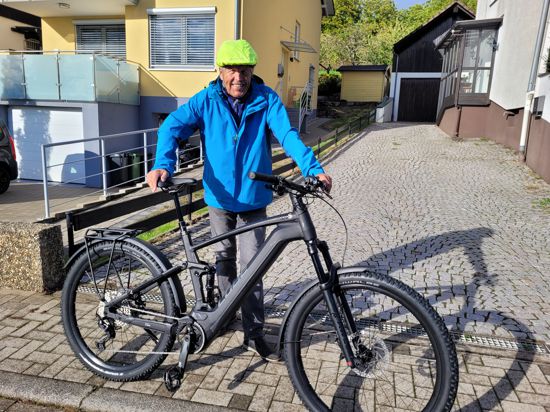 älter Mann mit Sturzhelm steht hinter E-Bike