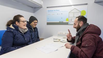 Glasfasermitarbeiter Mario Malafronte berät Stefanie und Bastian Iwanek im Infomobil vor dem Wössinger Rathaus