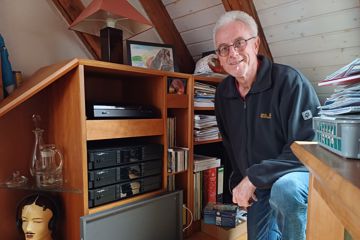 Helmut Patsch kniet neben seiner alten Radioanlage, die nach der Abschaltung des analogen Kabelradios nicht mehr funktioniert hat. 