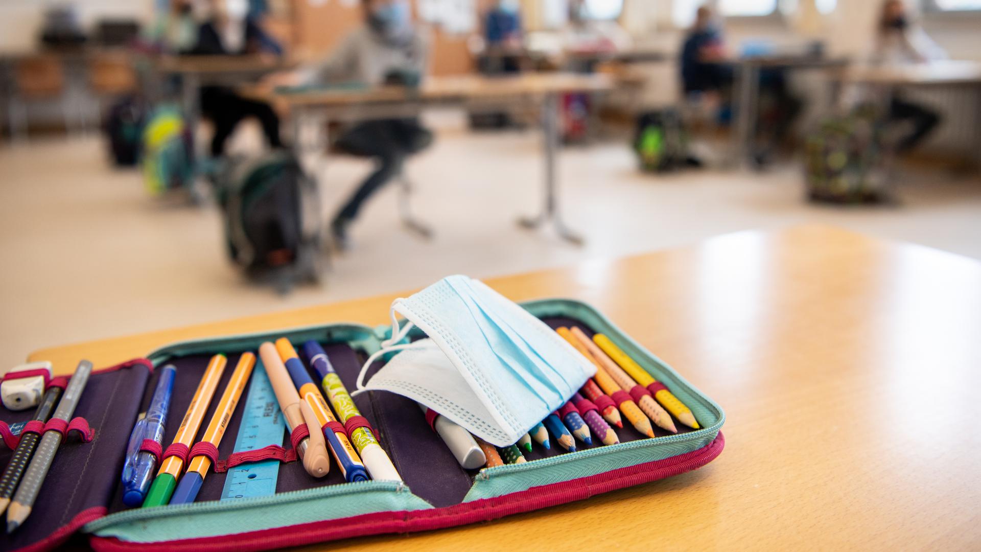 Der Ersatz-Mundschutz einer Schülerin liegt während des Unterrichts in einer vierten Klasse einer Grundschule auf dem Federmäppchen der Schülerin. 