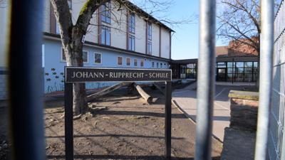 Ein Schild mit der Aufschrift „Johann-Rupprecht-Schule“ steht auf einem Schulhof